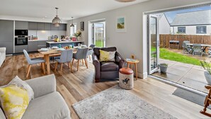 Une cuisine moderne avec un coin repas, un canapé en cuir et une vue sur le jardin arrière.