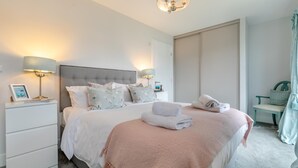 Une chambre moderne avec un grand lit, des lampes de chevet, une table de chevet, une chaise et une vue sur une porte coulissante.