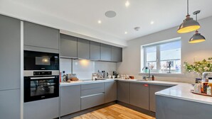 Une cuisine moderne avec des meubles gris, un four encastré, un évier et une fenêtre donnant sur un beau paysage.