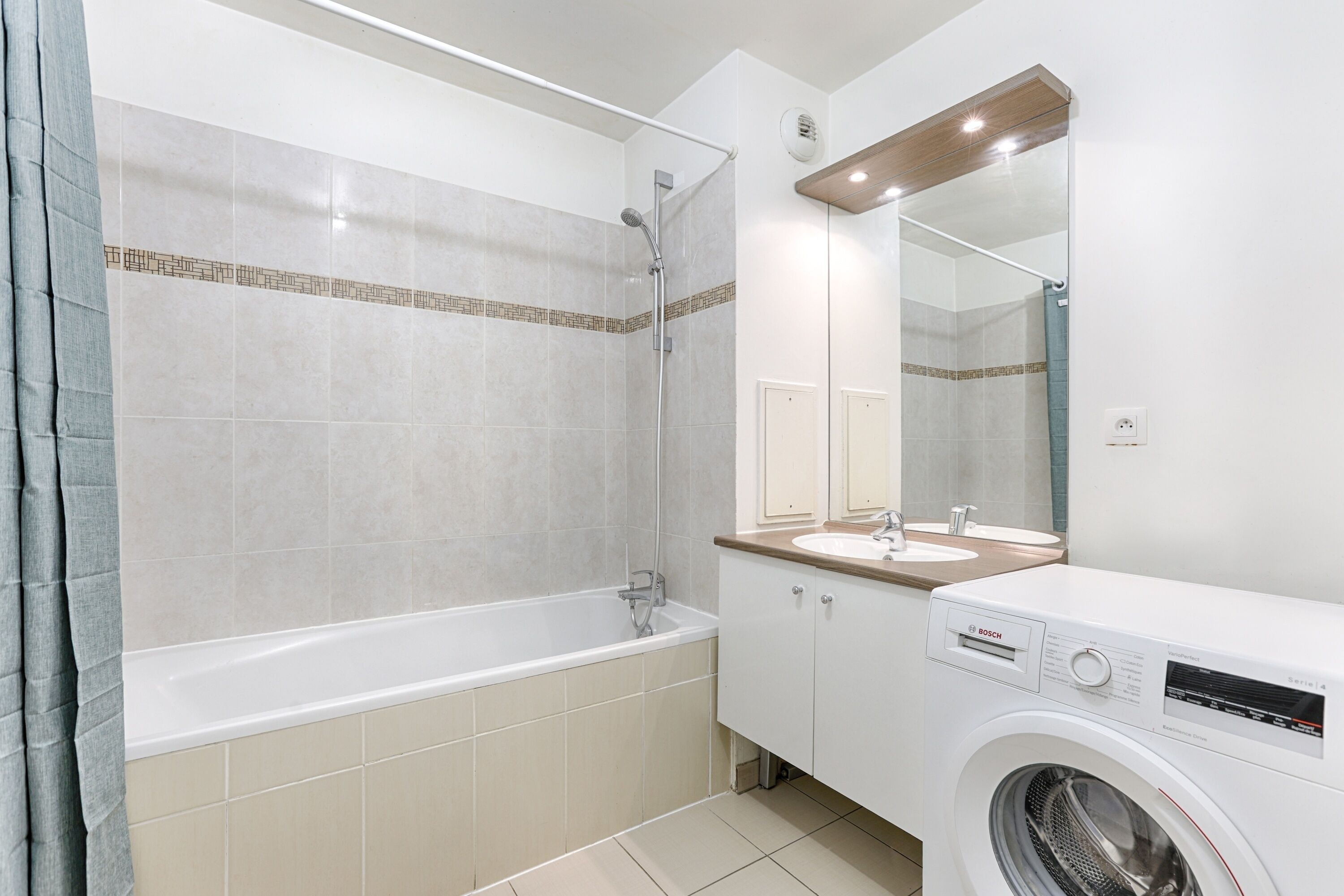 A modern bathroom with a bathtub, a shower, a sink, and a washing machine.