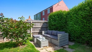 A patio area with a wicker sofa, a small table, and a potted plant. - 3 Bed in Bacton (oc-l2294) (Bacton)
