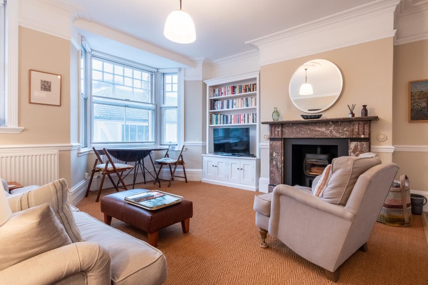 A cozy living room with a fireplace, a bookshelf, and a television.