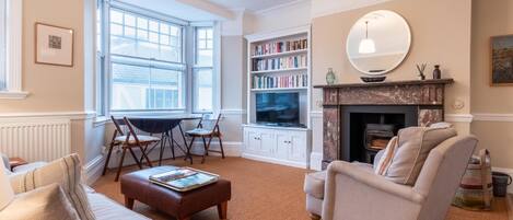 A cozy living room with a fireplace, a bookshelf, and a television.
