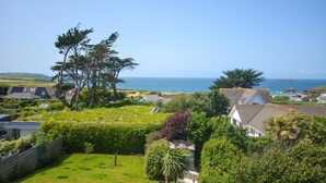 Un quartier résidentiel situé sur la côte, avec des maisons, une pelouse verdoyante et une vue sur la mer.