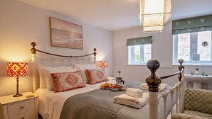 A bedroom with a bed, bedside tables, a lamp, a painting, a window, and a chair. - 3 Bed in Aldeburgh (oc-o5630) (Aldeburgh)