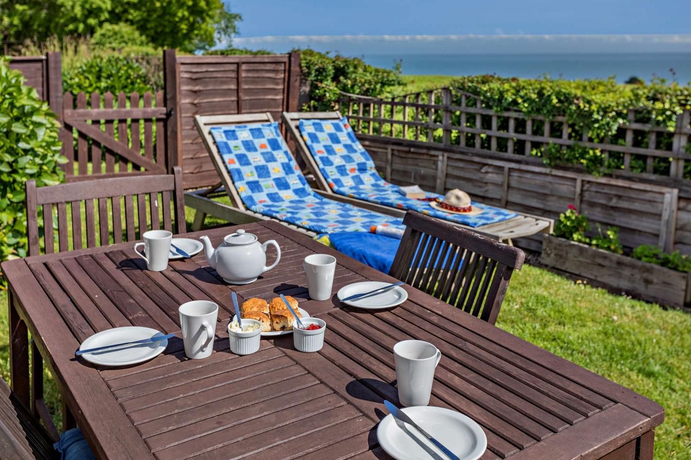A wooden table set for a meal with a view of the ocean.