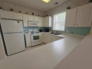 A modern kitchen with white cabinets, a built-in oven, a microwave, and a sink. - Amazing Barefoot Golf Resort 2Br 2Ba (North Myrtle Beach)