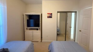 Un dormitorio con dos camas, un armario y una puerta que da a otra habitación.
