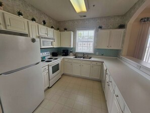 A kitchen with white cabinets, a microwave, stove, and a window with blinds. - Amazing Barefoot Golf Resort 2Br 2Ba (North Myrtle Beach)