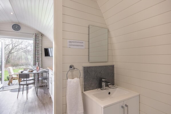 A modern bathroom with a white sink, a mirror, and a towel hanging on a rack.