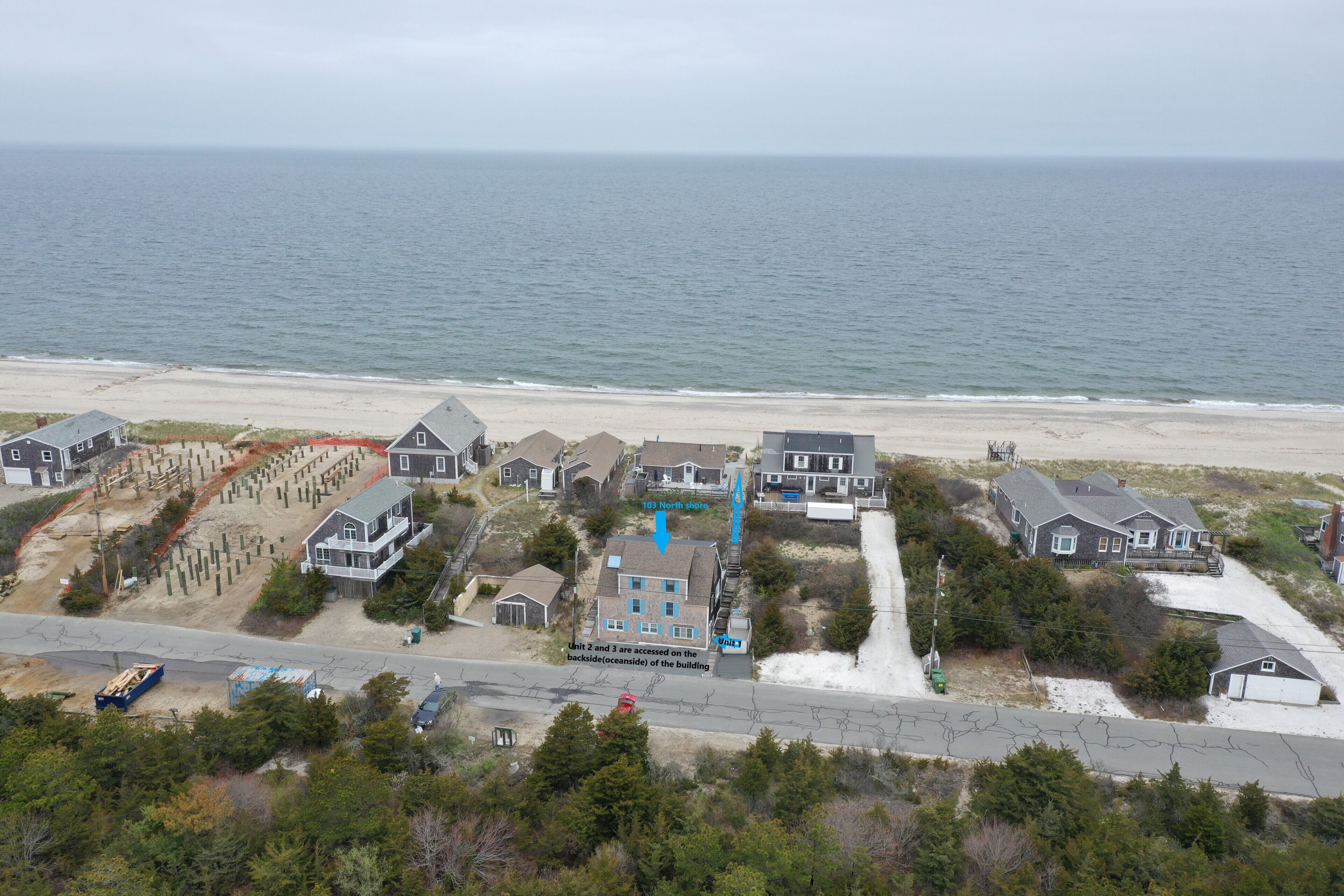 A coastal residential area with houses, a beach, and a road.
