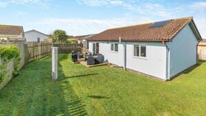 A single-story house with a tiled roof, a fenced yard, and a small patio area with outdoor furniture. - 3 Bed in St. Merryn (oc-l29062) (Saint Merryn)