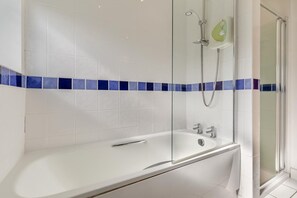 Een moderne badkamer met bad, douche en douchecabine.