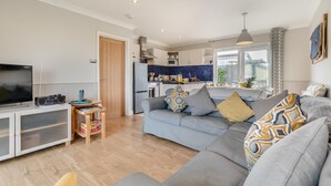 A modern living room with a grey sofa, a television, and a small wooden table. - 3 Bed in St. Merryn (oc-l29062) (Saint Merryn)