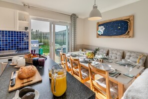 A modern kitchen with a dining area, a large window, and a view of the outdoors. - 3 Bed in St. Merryn (oc-l29062) (Saint Merryn)