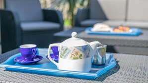 Uma mesa posta com um bule, xícara e açucareiro sobre uma bandeja azul.