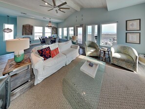 A spacious living room with a white sofa, a patterned armchair, a coffee table, and a ceiling fan. - Salty Kisses (Port Aransas)