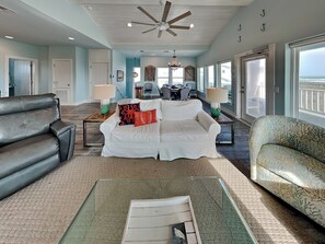 A spacious living room with a white sofa, a patterned armchair, and a glass coffee table. - Salty Kisses (Port Aransas)
