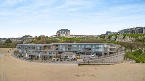A coastal building with multiple floors, a flat roof, and a beachside location. - 2 Bed in Tenby (oc-t29060) (Tenby)