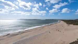 A wide beach with gentle waves, a clear sky, and distant landforms. - 2 Bed in Tenby (oc-t29060) (Tenby)