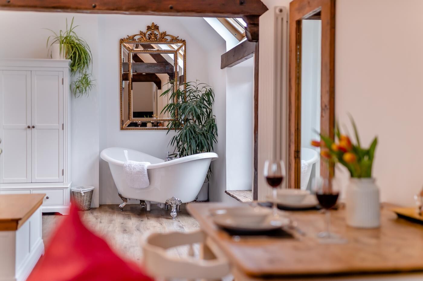 Un baño con una bañera blanca, un espejo grande y techo de madera.