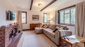 A living room with a fireplace, a sofa, a table with papers, and a TV mounted on the wall. - 2 Bed in Charing (oc-r29113) (Charing)