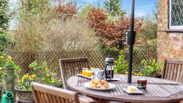An outdoor dining area with a table set for breakfast, including croissants, a coffee pot, and a glass of orange juice. - 2 Bed in Charing (oc-r29113) (Charing)