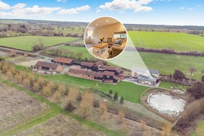 Vista aérea de una propiedad rural con varias construcciones, un extenso campo abierto y un estanque.