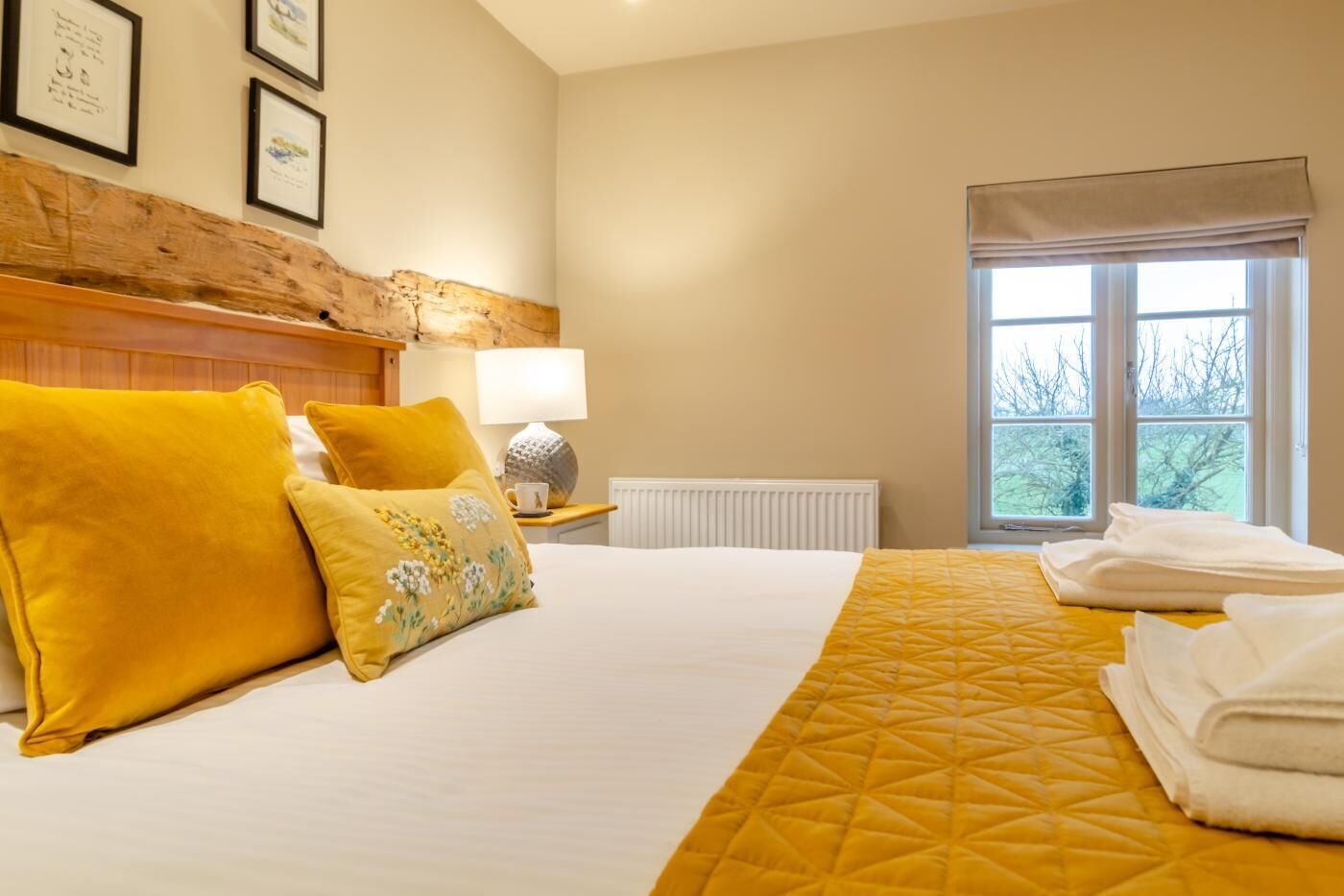 A hotel room with a bed, pillows, a lamp, a window, and a radiator.