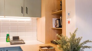 A kitchen with light blue cabinets, a wooden countertop, a hanging light fixture, a potted plant, and a small basket. - Your Urban Escape on Emilio Vaisse Studio (Providencia)