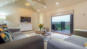 Un salon moderne avec un canapé, une table basse, un téléviseur et un balcon offrant une vue agréable.