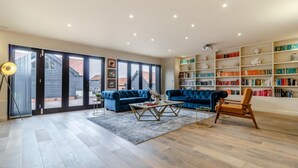 Un salon spacieux avec un canapé bleu, une table basse et une bibliothèque remplie de livres.