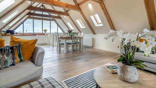 Ein geräumiges Loft mit hohen Decken, freiliegenden Holzbalken, einem Essbereich und Blick auf die Stadt.