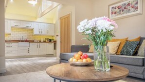 A living room with a round wooden coffee table, a vase with flowers, and a bowl of fruit. - 2 Bed in Heveningham (oc-w29029) (Heveningham)