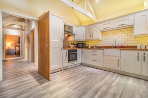 Eine moderne Küche mit weißen Schränken, einer Holztür und einer gefliesten Spritzschutzwand.