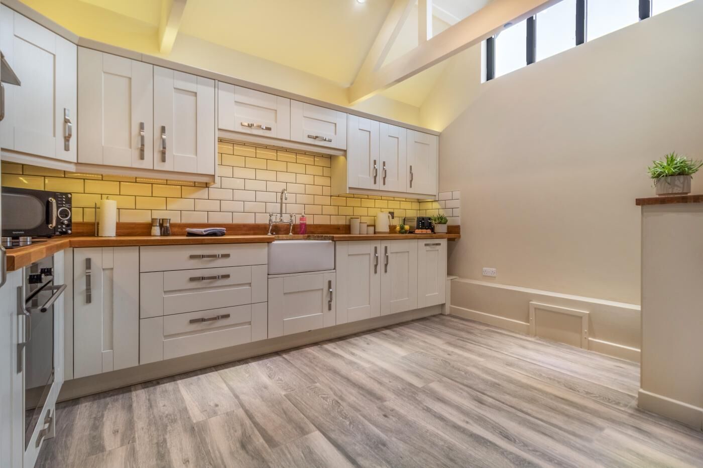 A kitchen with white cabinets, a wooden countertop, and a yellow-tiled backsplash.