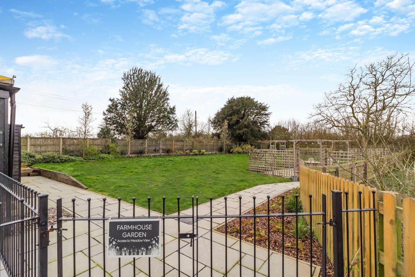 A fenced garden with a sign reading "Farmhouse Garden Access to Meadow View."