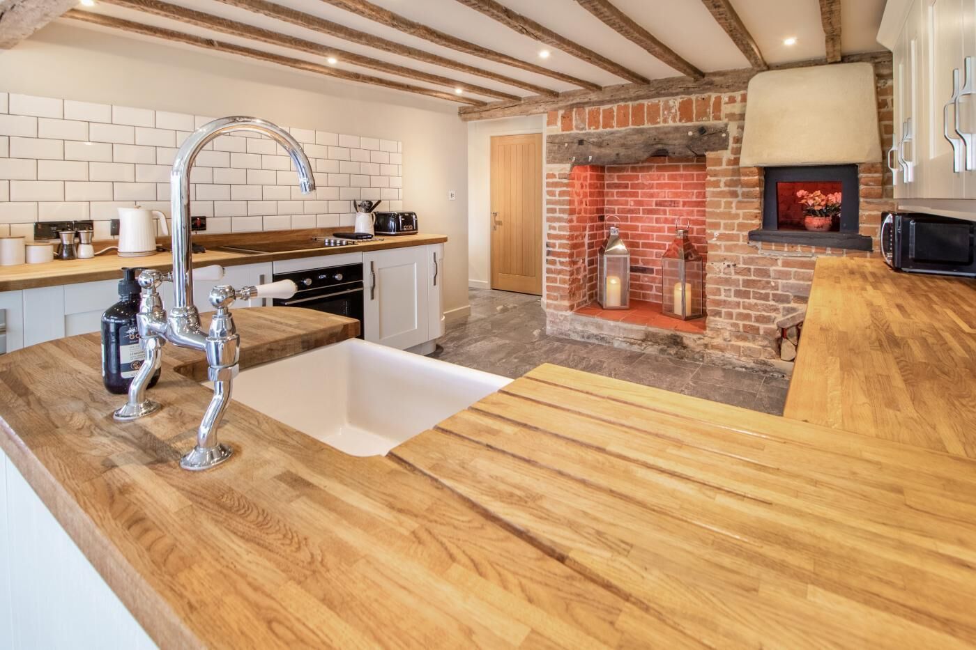 Een moderne keuken met een houten aanrecht, een RVS-gootsteen en een schouw met bakstenen.