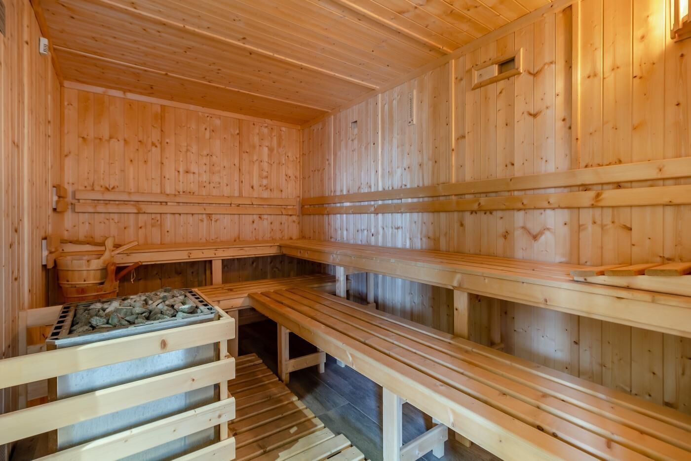 A wooden sauna with benches and a stone heating element.