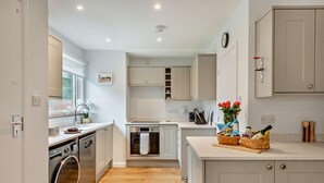 Cocina moderna con lavavajillas, horno y pileta. Se ve un ventanal con vista a la vegetación.