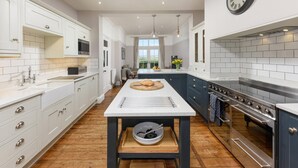 A modern kitchen with white cabinetry, a central island, and a large stove. - 5 Bed in Seahouses (oc-s29053) (Seahouses)