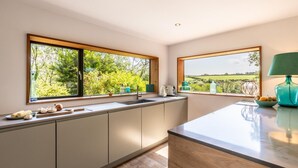 A modern kitchen with large windows, a sink, and a countertop. - 5 Bed in Little Petherick (oc-s29057) (Little Petherick)