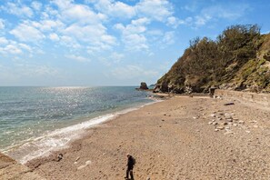 A pebbly beach with a rocky cliff and a clear sky. - 3 Bed in St. Austell (oc-c29089) (Charlestown)