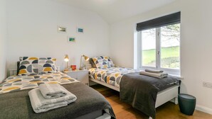 Ein Schlafzimmer mit zwei Betten, einem Fenster mit Aussicht und einem Nachttisch mit Lampe.