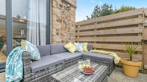 Ein modulares Sofa mit Kissen, ein Couchtisch mit Glasplatte und einer Schale mit Trauben sowie ein Blumentopf.