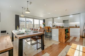 A modern kitchen with white cabinets, a wooden dining table, and a built-in island with a sink. - 3 Bed in Mawla (oc-l29154) (Mawla)