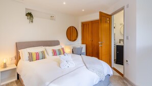 A bedroom with a large bed, a wooden wardrobe, a bedside table, and a small plant on the wall. - 1 Bed in Minster (oc-l29119) (Boscastle)