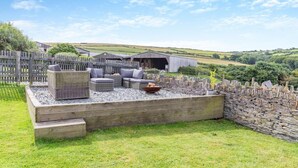 A patio area with wicker furniture, a fire pit, and a stone wall. - 1 Bed in Minster (oc-l29119) (Boscastle)