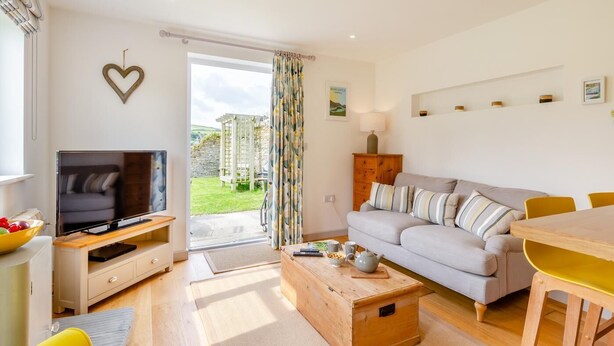 A modern living room with a TV, sofa, coffee table, and dining area. - 1 Bed in Minster (oc-l29119) (Boscastle)