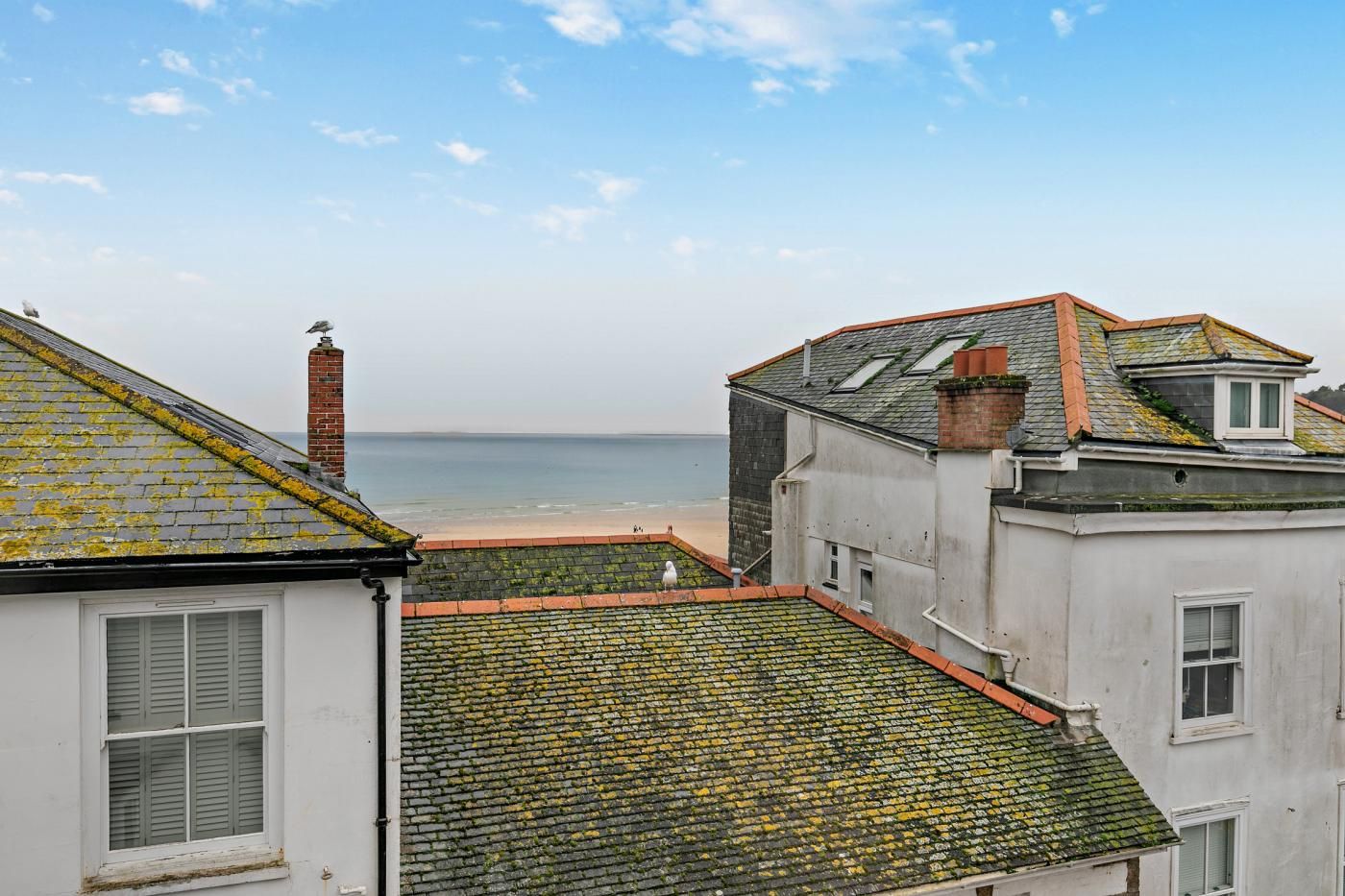 Un bâtiment situé sur la côte, avec vue sur la mer, une cheminée en briques et un toit recouvert de tuiles.